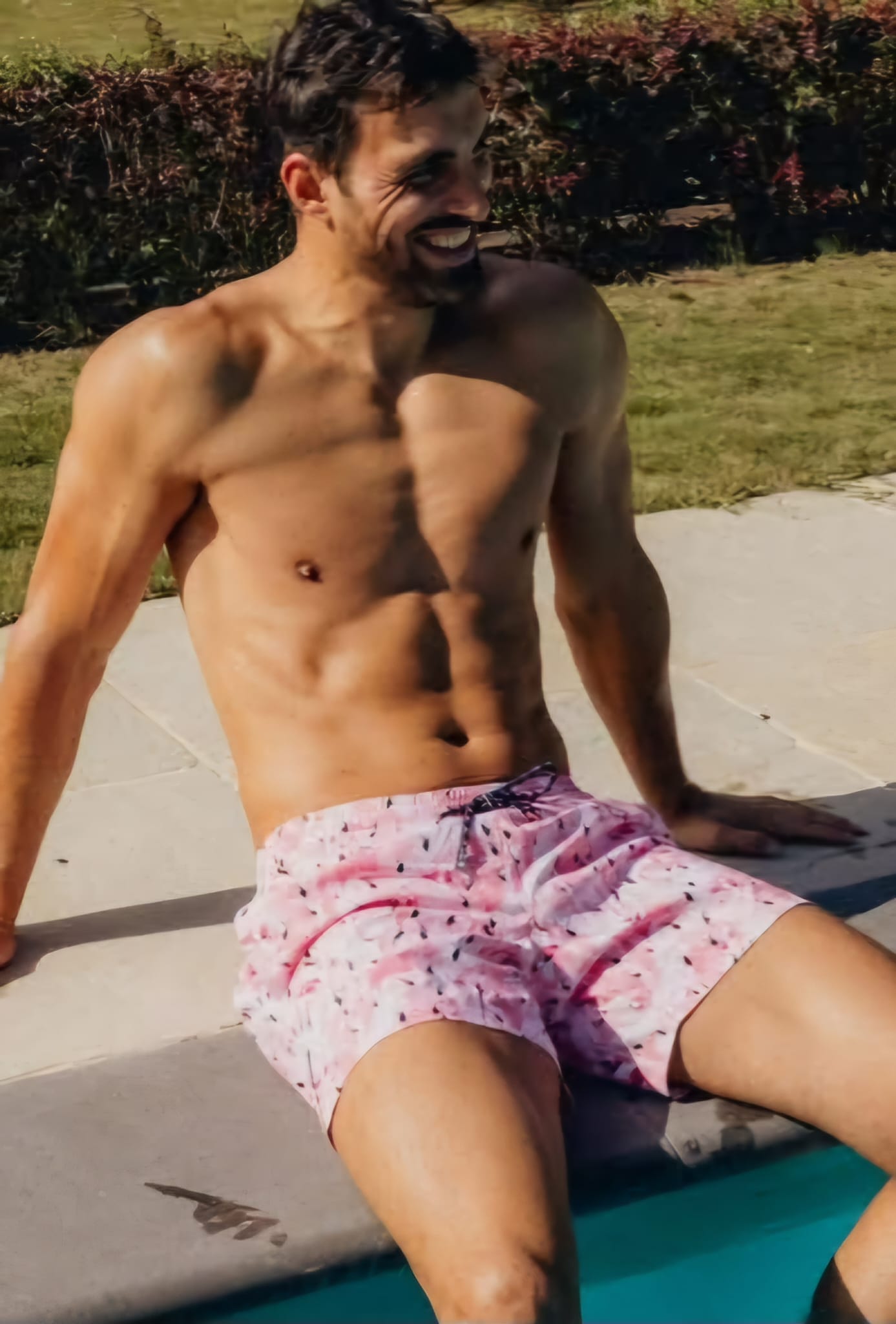 Homme portant un short de bain rose au bord d'une piscine
